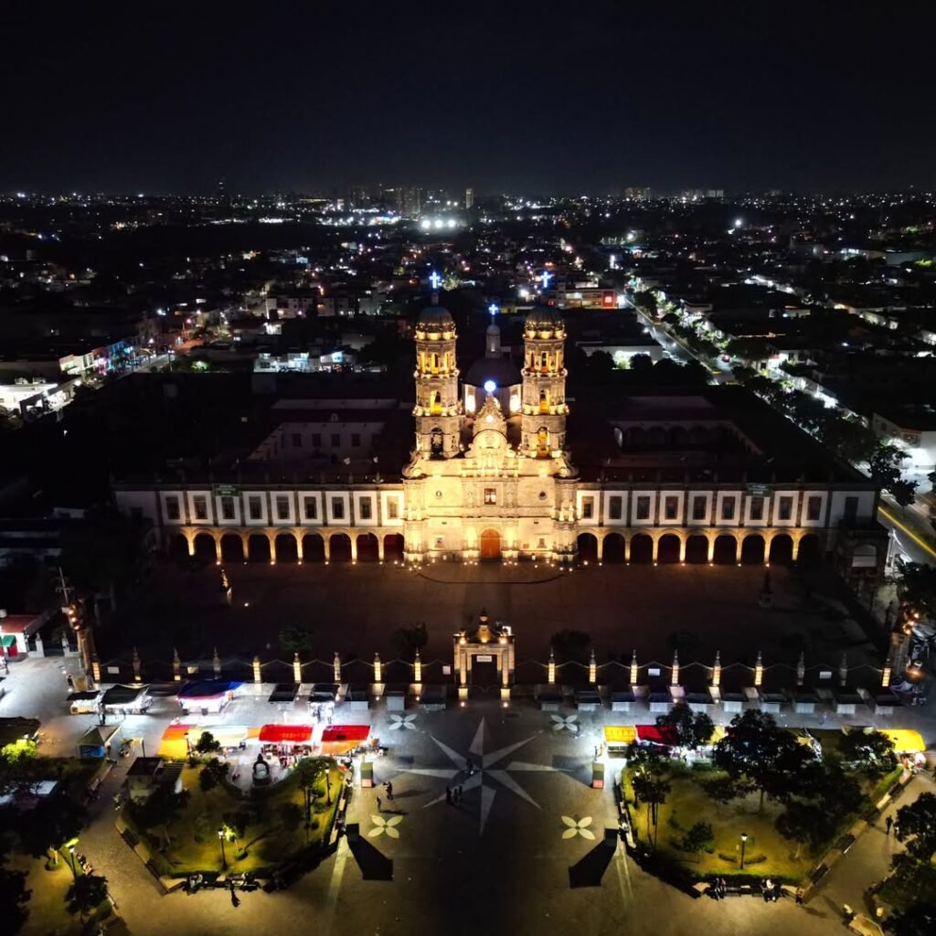 La Basílica de Zapopan brilla de noche. Una vista de dron captura su arquitectura dorada y la vida tranquila en la Plaza de las Américas